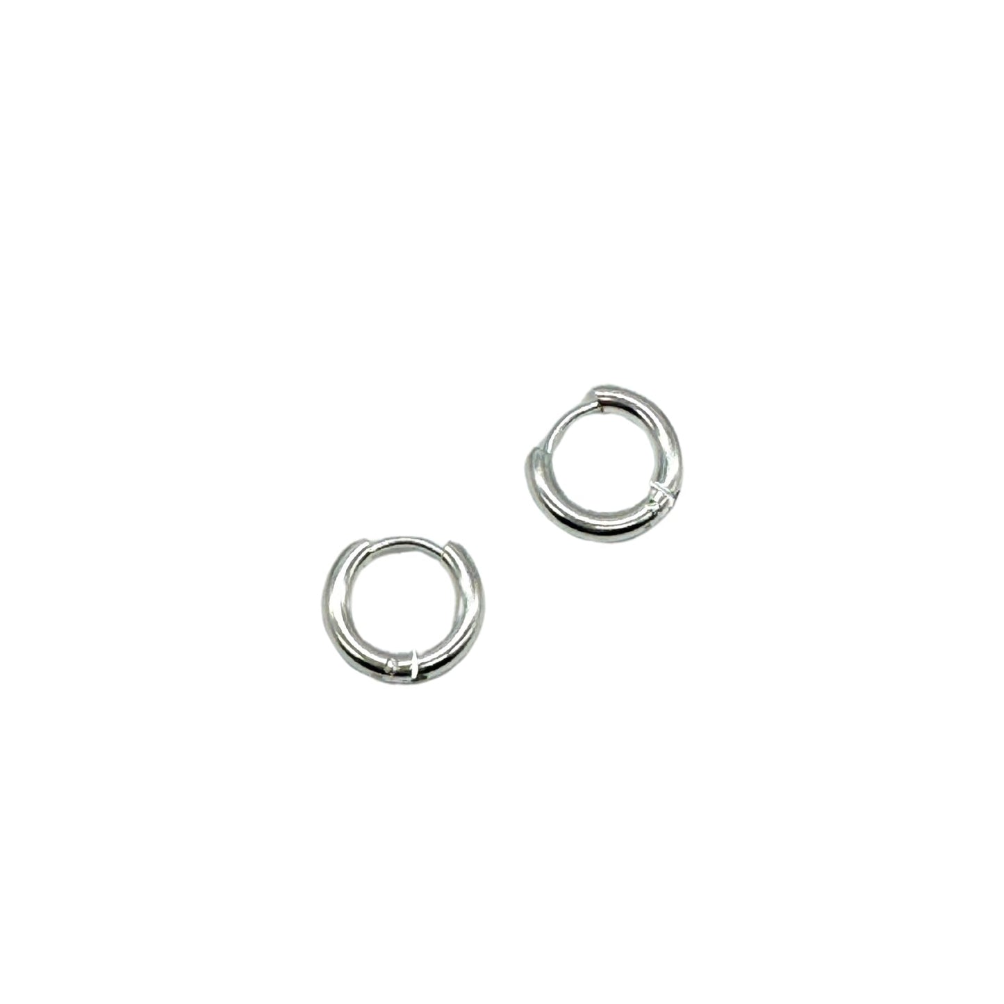 A pair of silver huggie hoop earrings on a white background