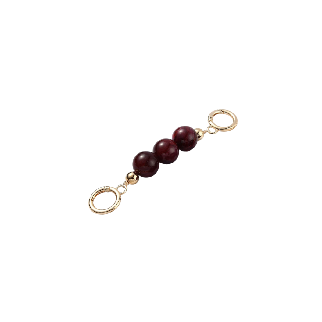 Gold charm with three red beads on a white background