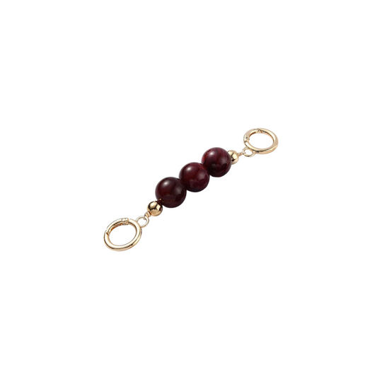 Gold charm with three red beads on a white background
