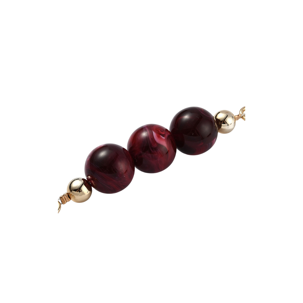 Beaded necklace with red beads and gold clasps on a white background