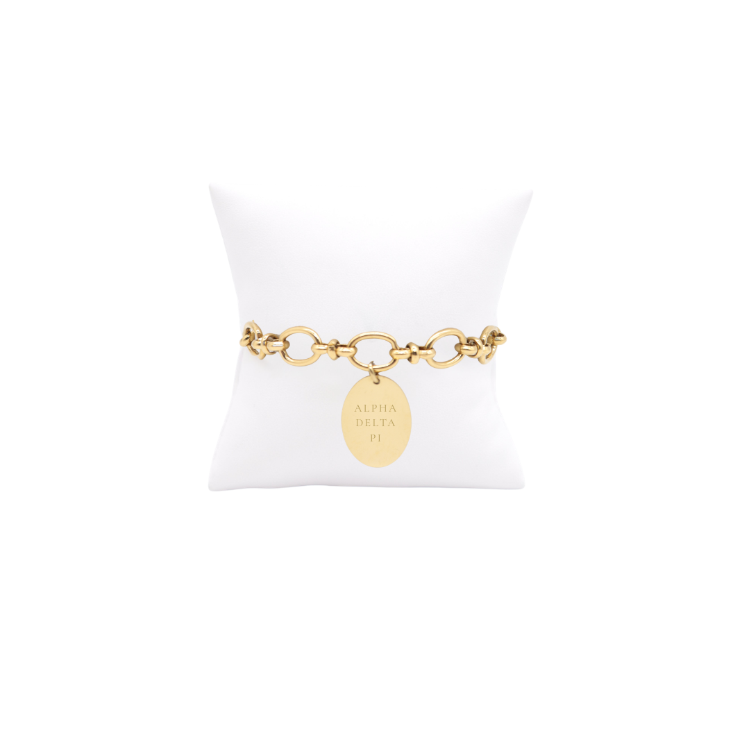 Alpha Delta Pi gold large link evermore bracelet with large oval charm with full sorority name on white pillow front view.