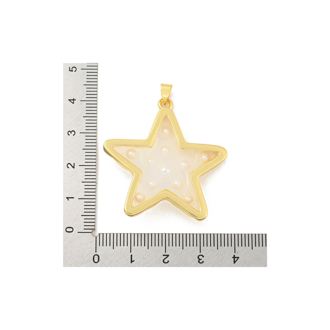 Gold star-shaped pendant with a white central design, next to a ruler for scale on a white background.