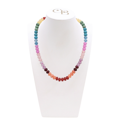 Multicolored beaded necklace on a white stand with a visible brand logo.