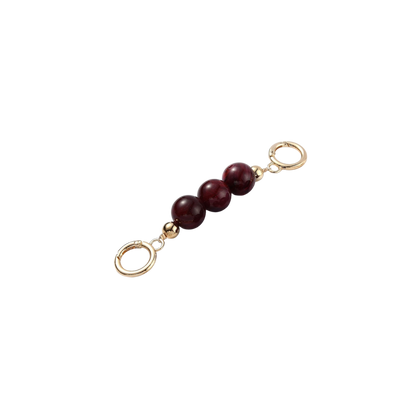 Gold charm with three red beads on a white background