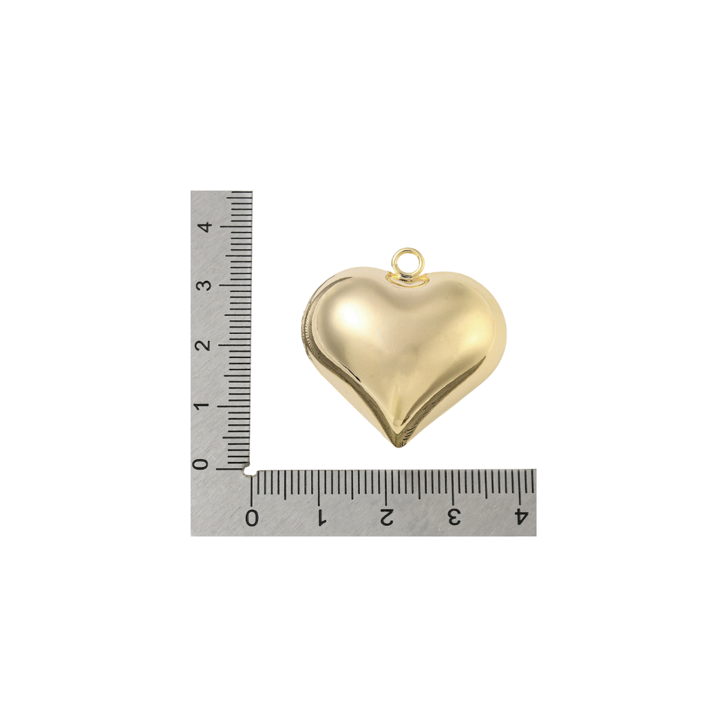 Gold heart-shaped pendant next to a ruler on a white background