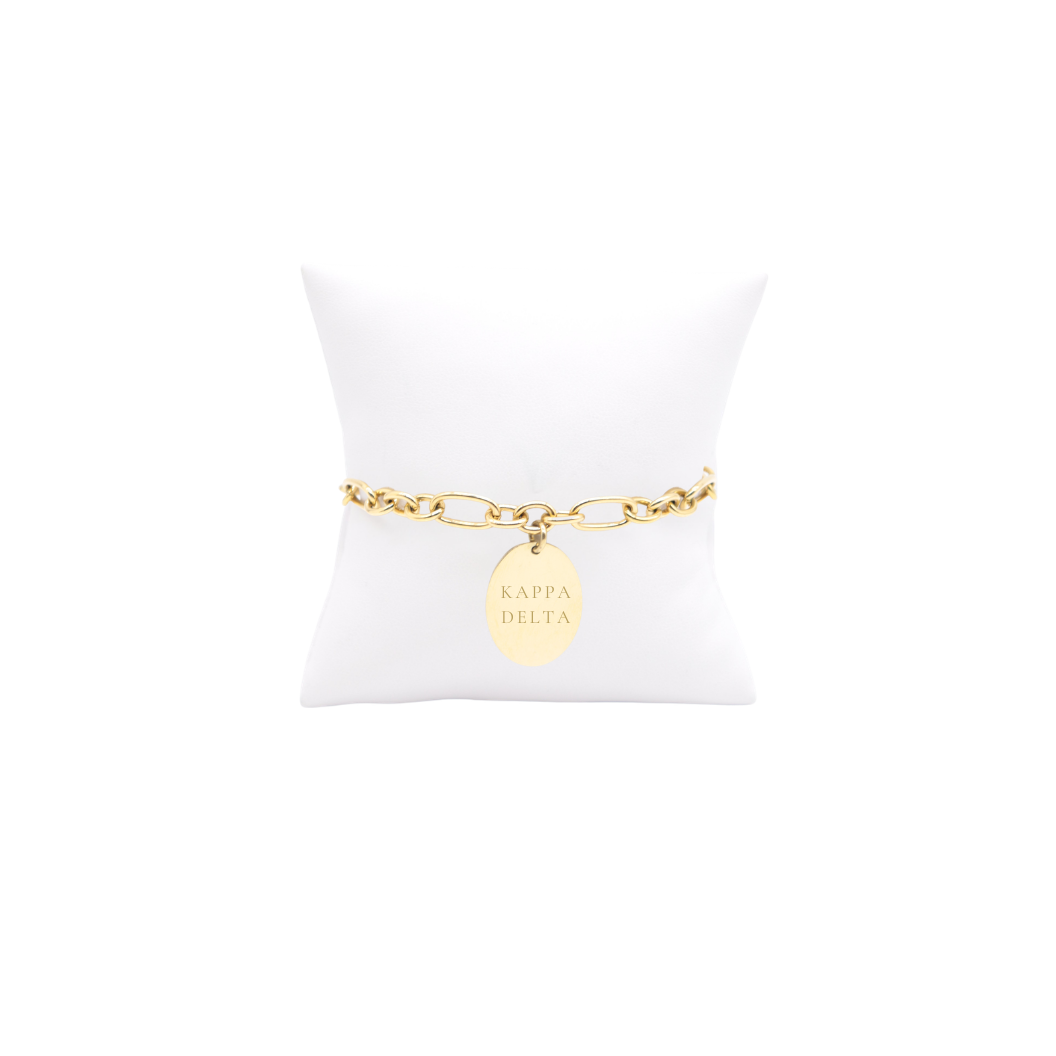 Kappa Delta gold large link Keepsake bracelet with large oval charm with full sorority name on white pillow front view