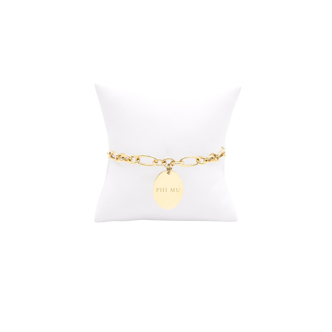 Phi Mu gold large link Keepsake bracelet with large oval charm with full sorority name on white pillow front view