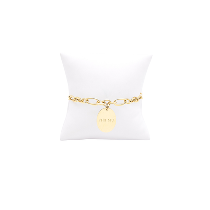 Phi Mu gold large link Keepsake bracelet with large oval charm with full sorority name on white pillow front view