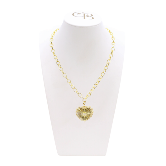 Gold necklace with a heart-shaped pendant on a white stand with a visible brand logo.