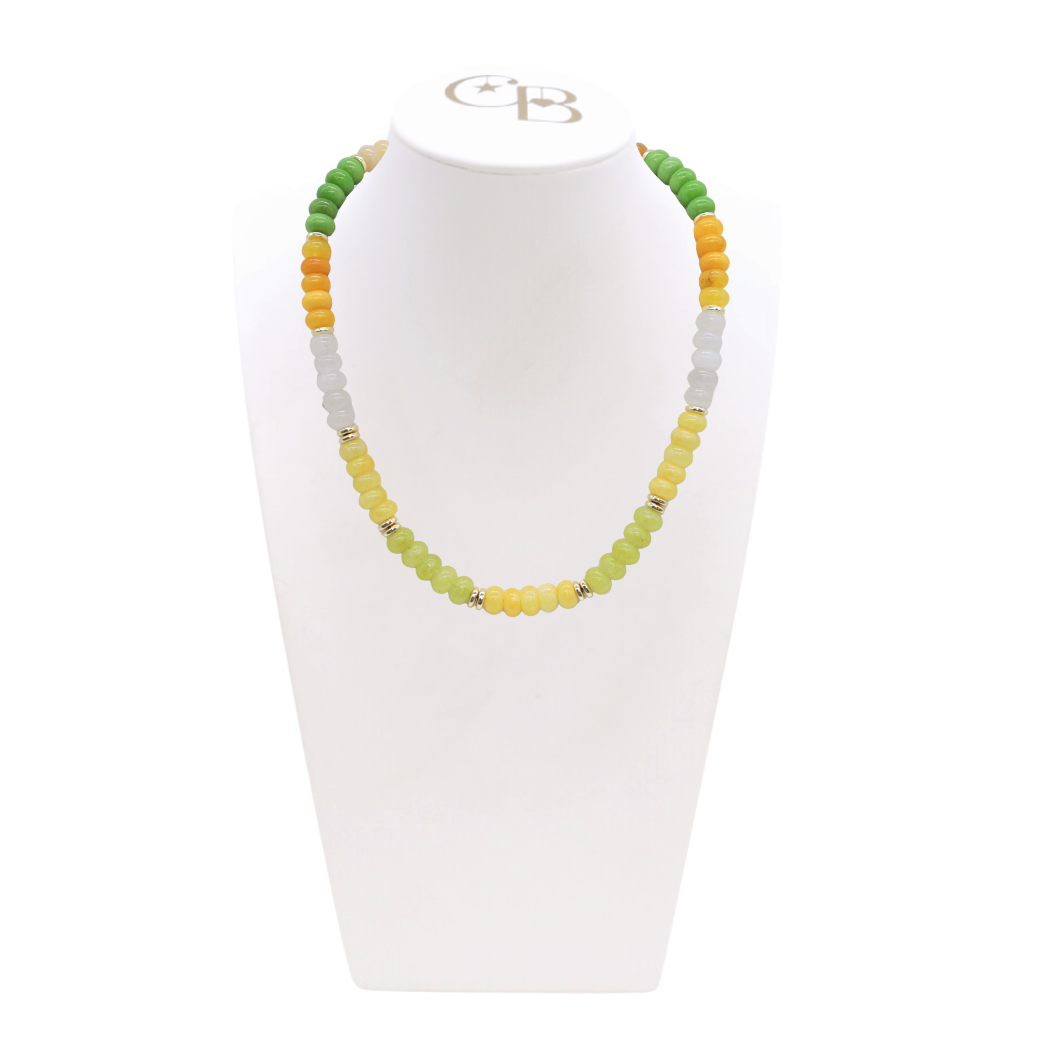 Necklace with green, yellow, and gray beads on a white stand with a visible brand logo. Lemon Drop Daze Beaded Necklace