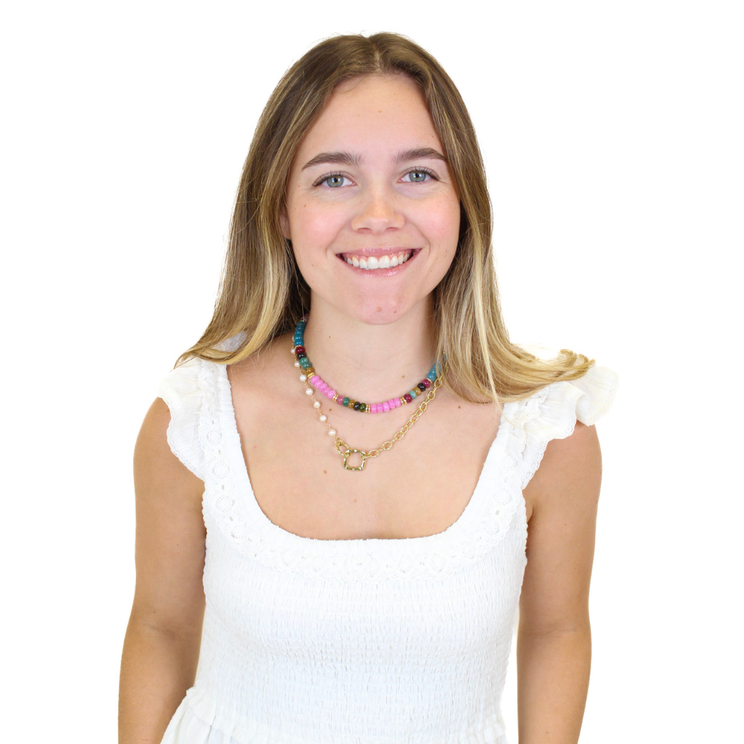 Woman wearing multiple necklaces on a white background. 