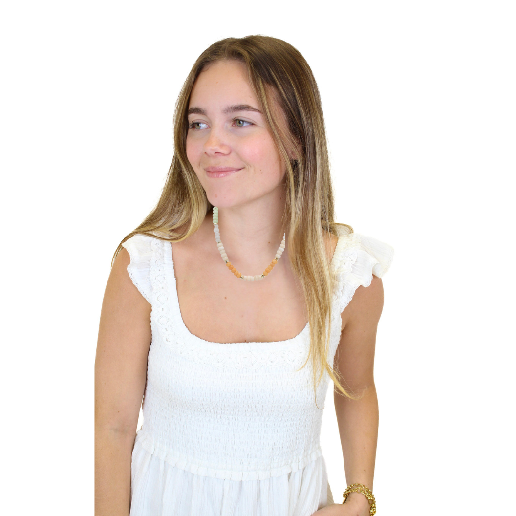 Woman wearing a white dress with ruffled sleeves on a white background.Mimosa by the Sea Beaded Necklace