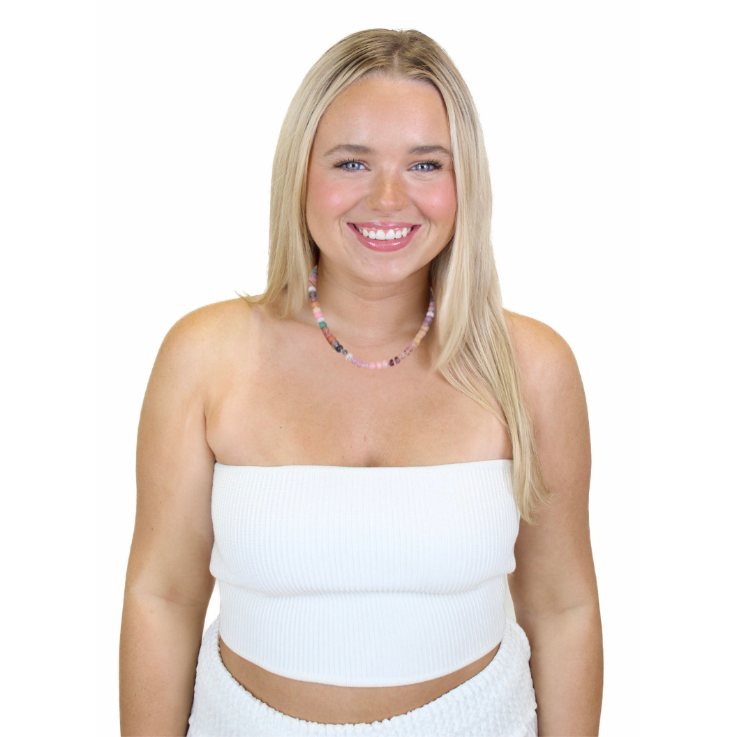 Woman wearing a white strapless top and skirt with a necklace on a white background.  Seashell Whisper Beaded Necklace
