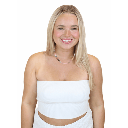 Woman wearing a white strapless top and skirt with a necklace on a white background.  Seashell Whisper Beaded Necklace