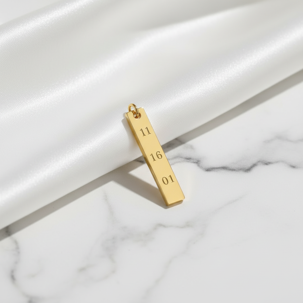 Gold pendant with engraved numbers on a marble surface