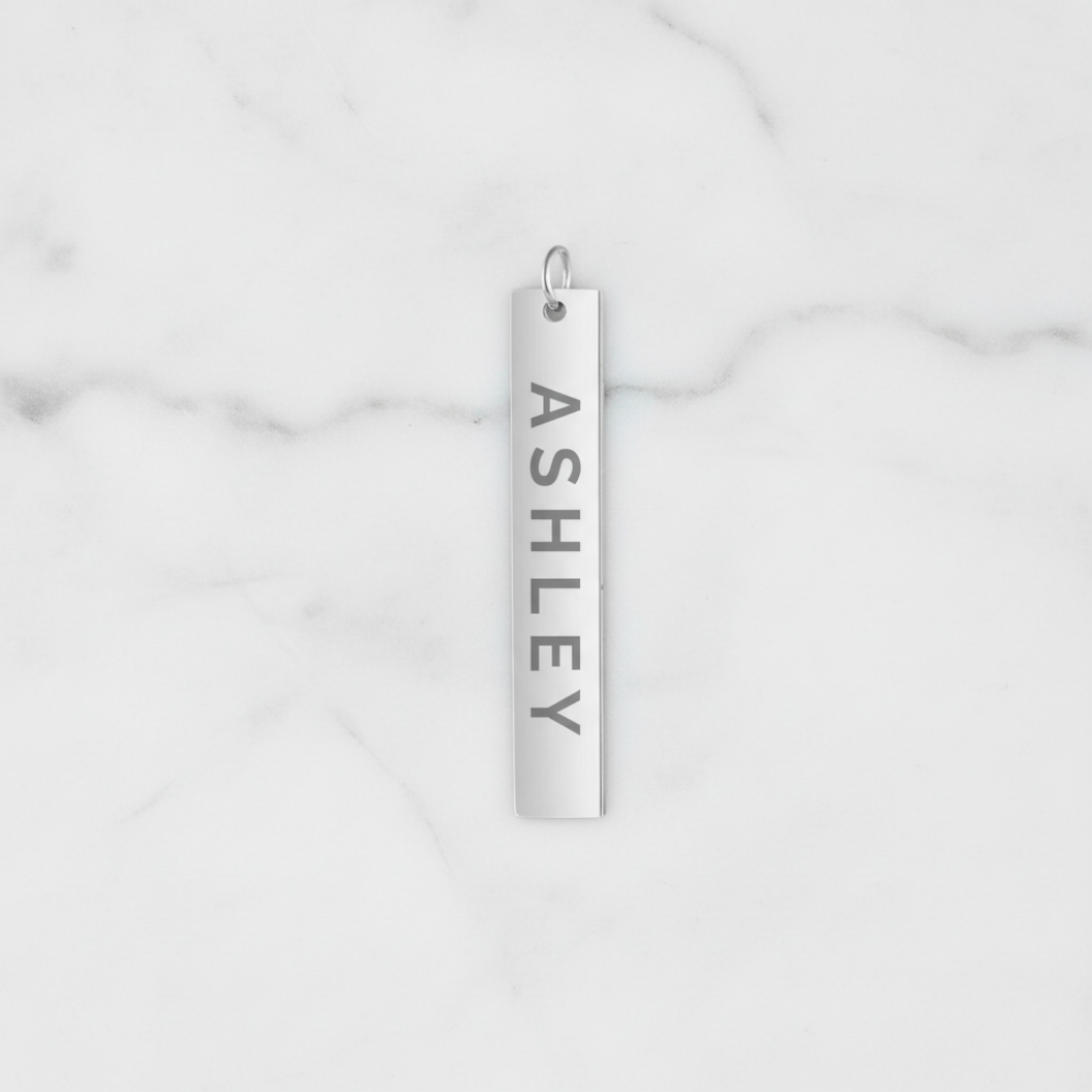 Silver pendant with 'ASHLEY' engraved on a marble background