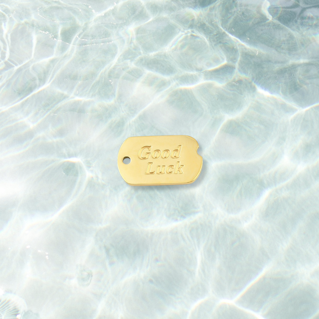 Gold Good Luck Dog Tag Charm on water background 