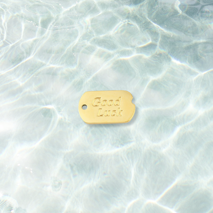 Gold Good Luck Dog Tag Charm on water background 