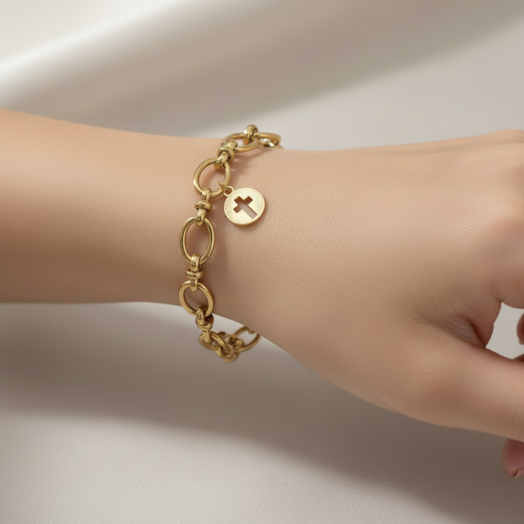 Gold Cut Out Cross Charm on a bracelet