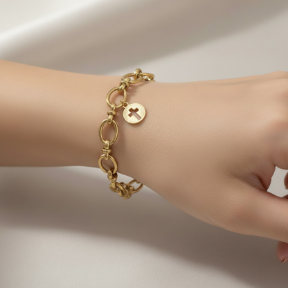 Gold Cut Out Cross Charm on a bracelet