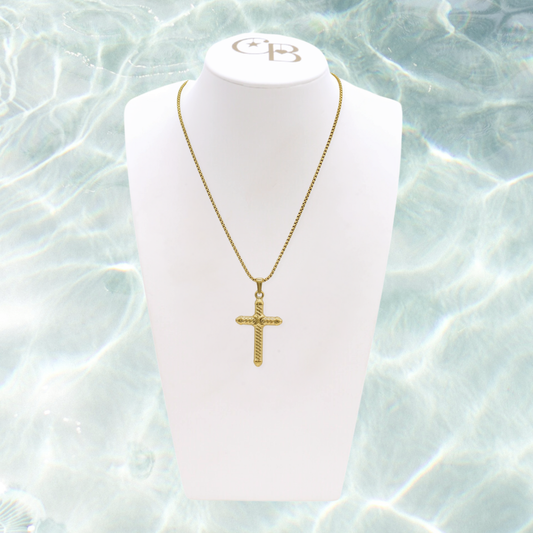 Gold necklace with a cross pendant on a white mannequin bust against a water-like background