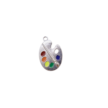 A silver pendant charm designed to look like a paint palette with multiple color wells and a small brush.