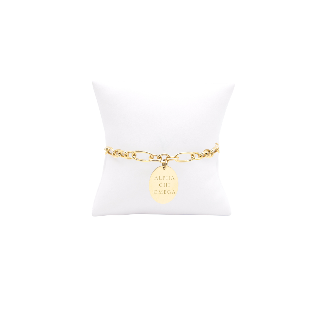 Alpha Chi Omega gold large link Keepsake bracelet with large oval charm with vertical greek letters on white pillow front view