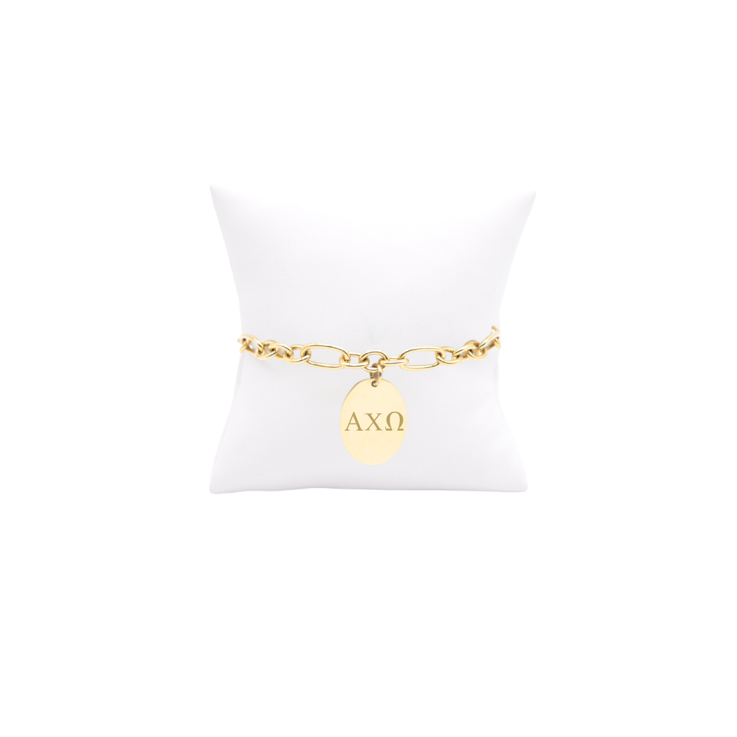 Alpha Chi Omega gold large link Keepsake bracelet with large oval charm with horizontal greek letters on white pillow front view