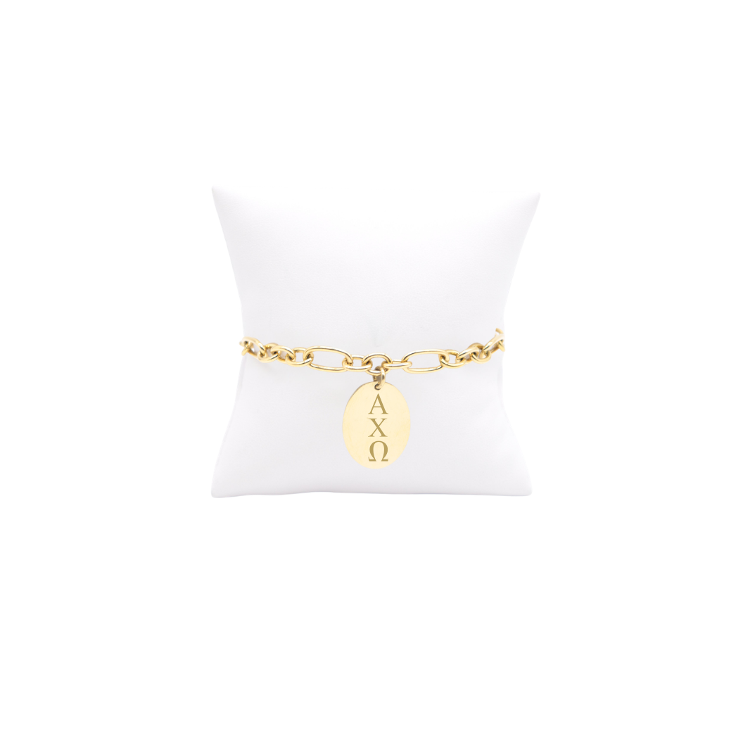 Alpha Chi Omega gold large link Keepsake bracelet with large oval charm with vertical greek letters on white pillow front view