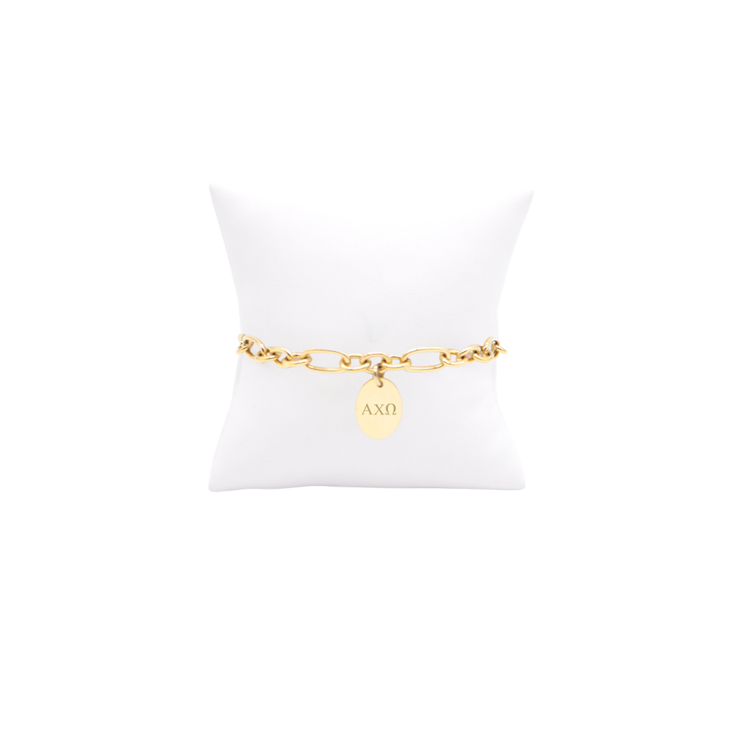 Alpha Chi Omega gold link Keepsake bracelet with small oval charm with horizontal greek letters on white pillow front view