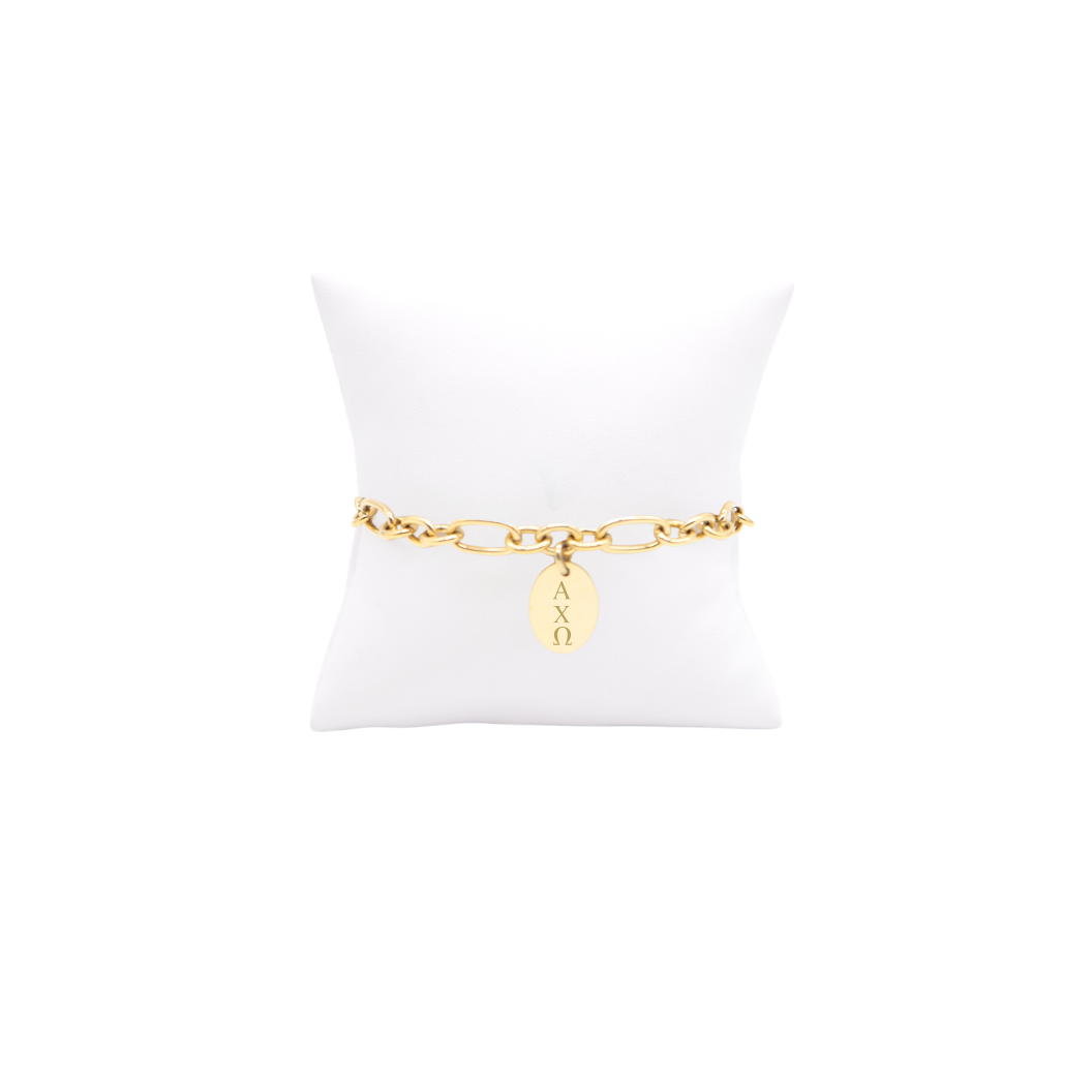 Alpha Chi Omega gold link Keepsake bracelet with small oval charm with vertical greek letters on white pillow front view