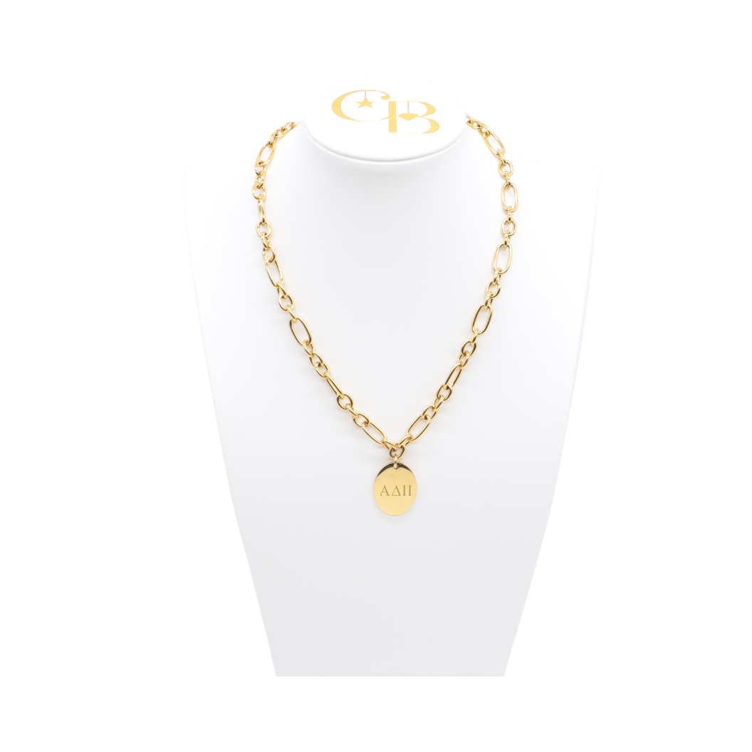 Alpha Delta Pi gold large link Keepsake necklace with large oval charm with horizontal greek letters on white pillow front view.