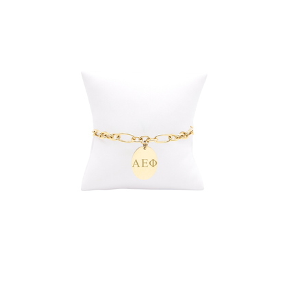 Alpha Epsilon Phi gold large link keepsake bracelet with large oval charm with vertical/stacked greek letters on white pillow front view