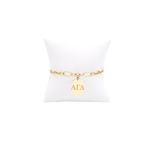 Alpha Gamma Delta gold large link keepsake bracelet with large oval charm displayed on white pillow front view with horizontal greek letters
