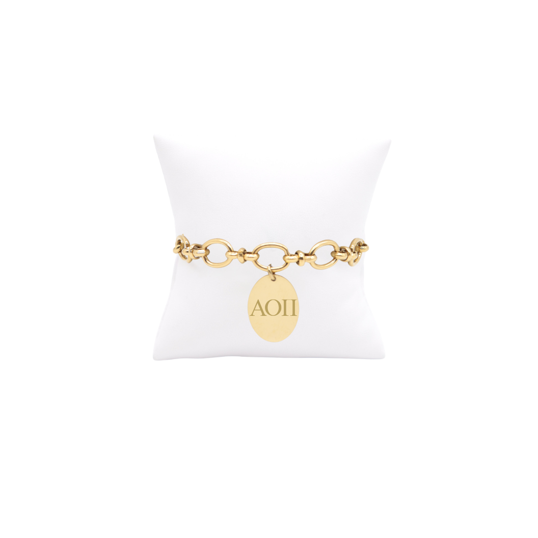 Alpha Omicron Pi gold large link Evermore bracelet with large oval charm with horizontal greek letters on white pillow front view