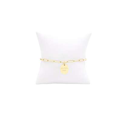 Alpha Phi gold link storyline bracelet with small oval charm with full sorority name on white pillow front view
