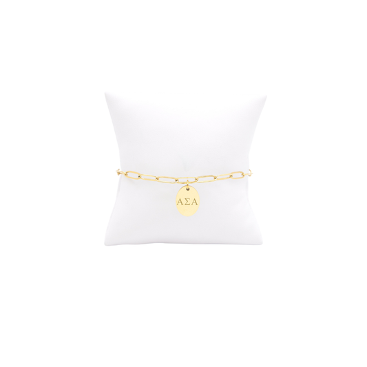 Alpha Sigma Alpha gold link storyline bracelet with small oval charm displayed on white pillow front view with horizontal greek letters