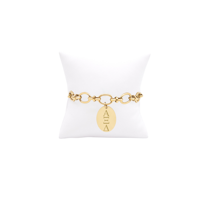 Alpha XI Delta gold large link evermore bracelet with large oval charm displayed on white pillow front view with vertical/stacked greek letters