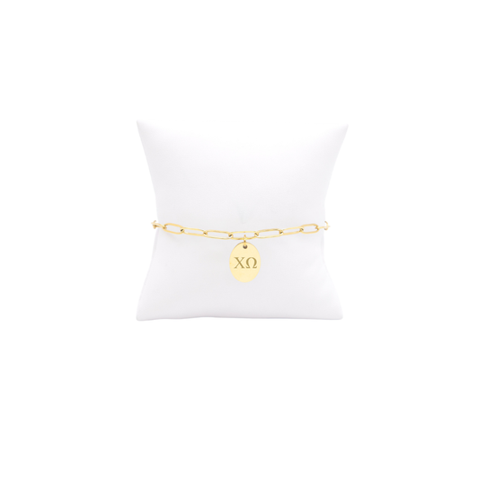 Chi Omega gold link storyline bracelet with small oval charm with horizontal greek letters on white pillow front view
