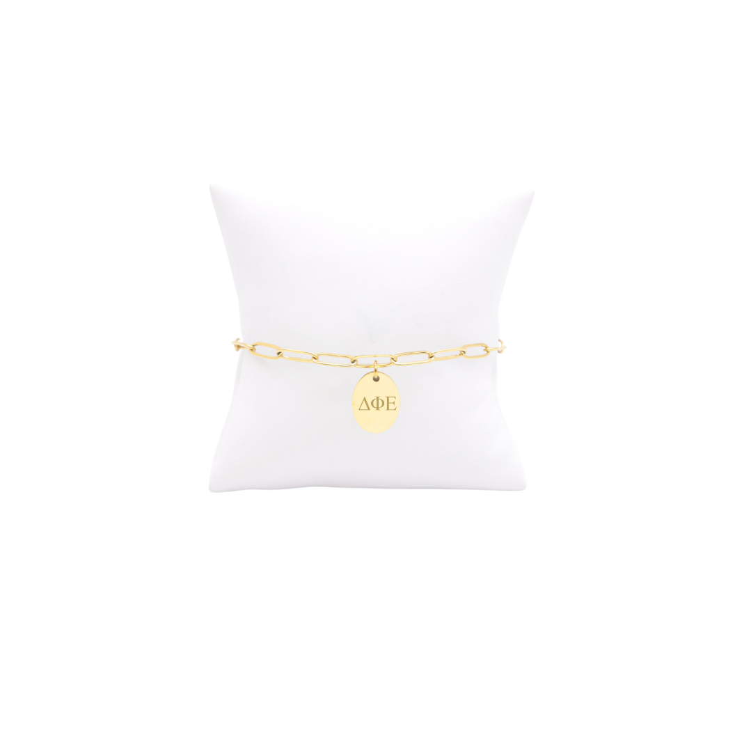 Delta Phi Epsilon gold link storyline bracelet with small oval charm displayed on white pillow front view vertical/stacked greek letters