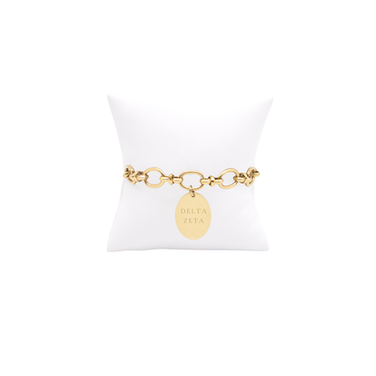 Delta Zeta gold large link evermore bracelet with large oval charm with full sorority name on white pillow front view