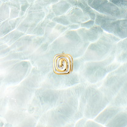 Gold and silver spiral charm with a modern mixed metal swirl design on a shimmering water background.