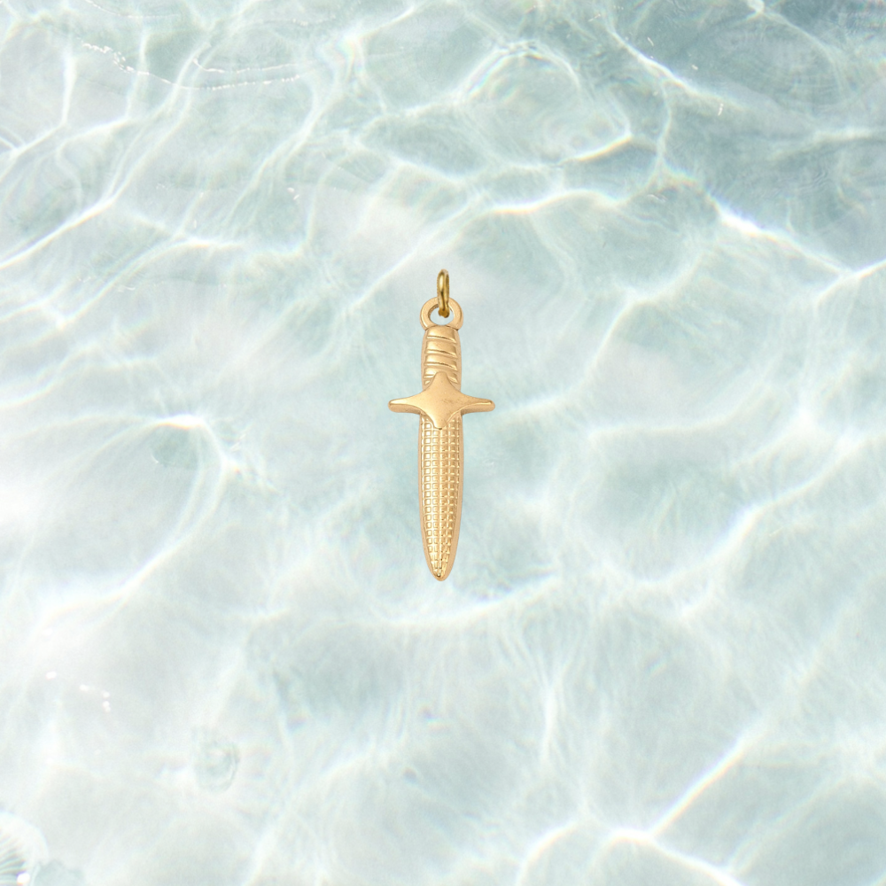 Gold dagger charm featuring engraved blade details and a polished finish on a shimmering water background.