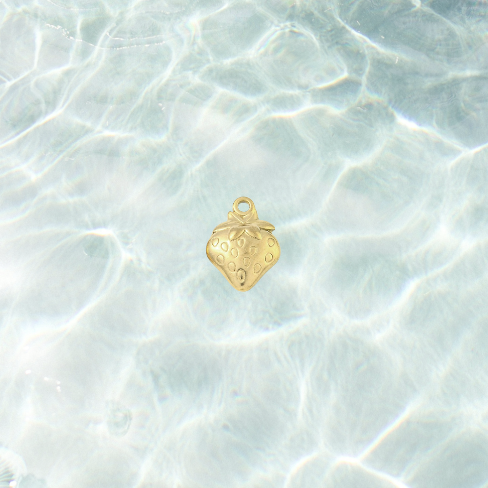 Gold fresh picked strawberry charm with a polished finish, embossed seed details and leafy top design on a waterproof background