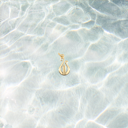 Gold lyre charm on a shimmering water background