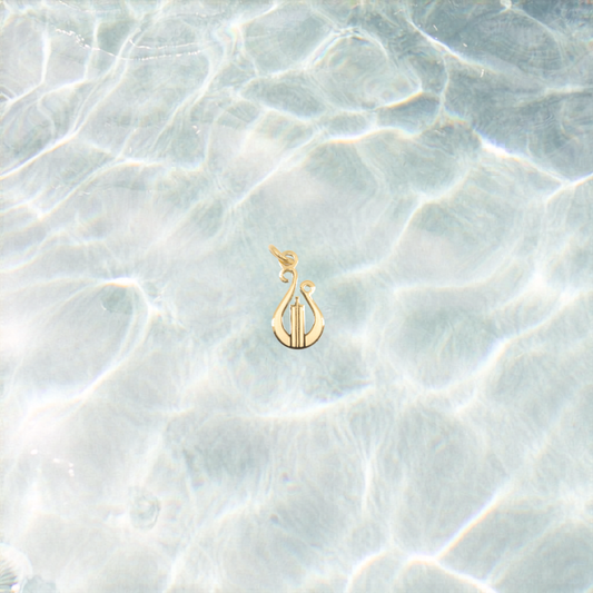 Gold lyre charm on a shimmering water background
