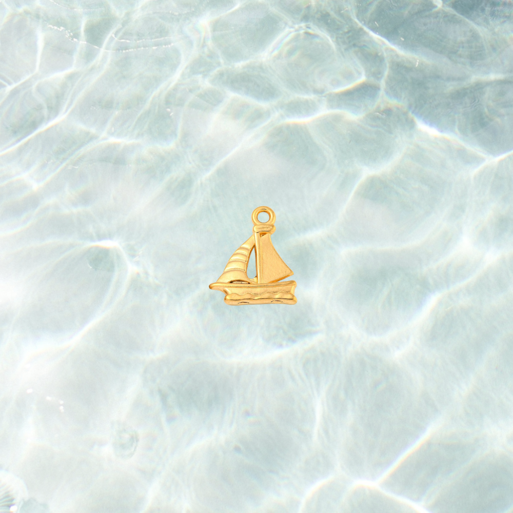 Gold nautical sailboat charm on waterproof background