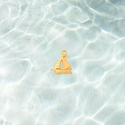 Gold nautical sailboat charm on waterproof background