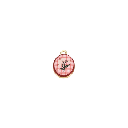 Gold pink checkered floral oval charm featuring a delicate white flower design on a pink gingham background