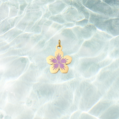Gold flower charm featuring a five-petal flower design with a lavender purple center on a shimmering water background.